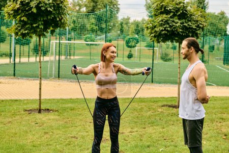 Eine entschlossene Frau in Sportbekleidung trainiert mit einem Personal Trainer in einer lebendigen Parklandschaft.
