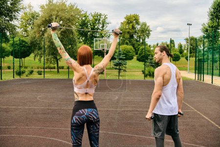 Photo for A man and a woman in sportswear, guided by a personal trainer, stand on a court with determination and motivation. - Royalty Free Image