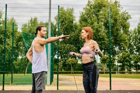 A woman, dressed in sportswear, stand on a court with determination and motivation, being coached by personal trainer.