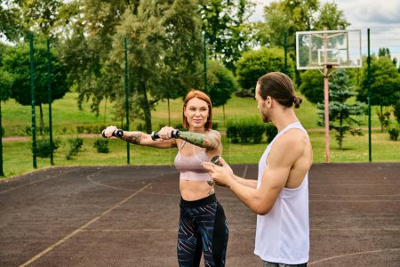 Un hombre y una mujer, en ropa deportiva haciendo ejercicio con pesas, determinación