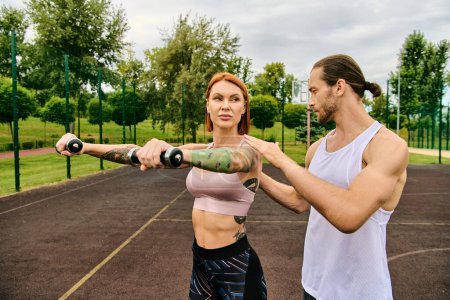 Foto de Un hombre y una mujer decididos en ropa deportiva haciendo ejercicio con pesas - Imagen libre de derechos