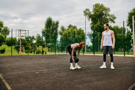 A woman in sportswear, guided by a personal trainer, demonstrate determination and motivation on the court.