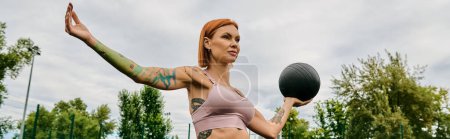 A woman in sportswear, holding a medicine ball outdoors, determination and motivation