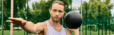A man in sportswear, holding a black ball in his right hand, is focused on his outdoor exercise routine.