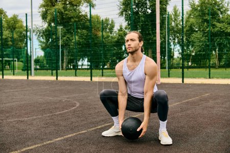 Téléchargez les photos : Un homme en tenue de sport est assis sur un court, tenant une balle, réfléchissant à son prochain mouvement dans le jeu. - en image libre de droit