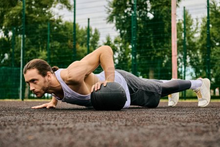 Photo for A man in sportswear performs push ups on the ground with determination as a personal trainer coaches him outdoors. - Royalty Free Image