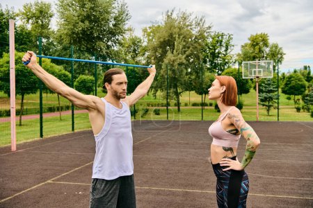 Un hombre y una mujer en ropa deportiva están de pie en una cancha, centrándose en su sesión de entrenamiento con determinación y motivación.