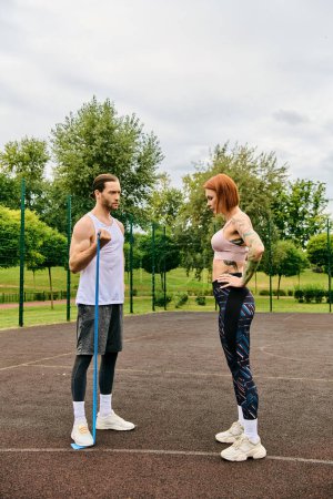 A determined man and woman in sportswear stand poised on a court, ready for a challenging workout session