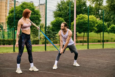 A determined man and woman in sportswear stand on a tennis court, focusing on their exercise routine.