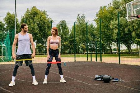 A man and woman in sportswear having resistance band training, showing determination and motivation
