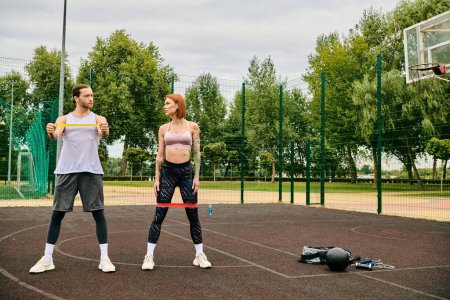 Un hombre y una mujer en ropa deportiva hacen ejercicio en una cancha mostrando determinación y motivación.