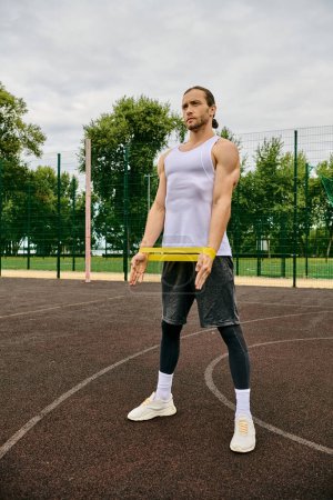 Un hombre en ropa deportiva se para en una cancha de tenis, entrenamiento de banda de resistencia