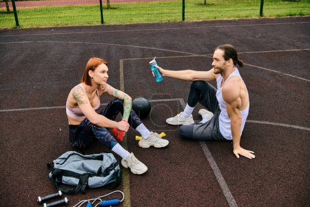 A personal trainer guides a man and woman in sportswear as they exercise on a tennis court with determination and motivation.