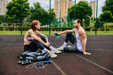 Téléchargez les photos : Un homme et une femme en entraînement de vêtements de sport ensemble sur un terrain de basket-ball, montrant détermination et motivation. - en image libre de droit