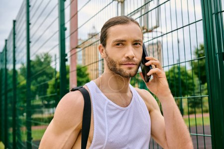 Un hombre decidido en ropa deportiva habla en su teléfono celular en un entorno al aire libre mientras muestra su fuerza y concentración.