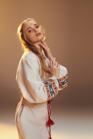 Eine junge Frau in einem traditionellen elfenbeinfarbenen Kleid posiert in einer märchenhaften und phantasievollen Studiokulisse in ausgewogener und eleganter Pose.