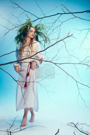 Young mavka in ornate white dress delicately balances a plant on her head in a whimsical studio setting.