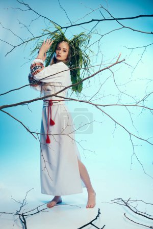 Eine junge Frau in weißem Kleid und traditionellem Outfit steht anmutig vor einem mystischen Baum in einem Atelier.