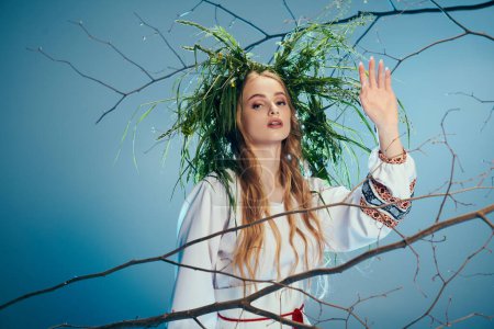Una joven vestida de mavka, con una corona, de pie frente a un árbol en un estudio de hadas y fantasía.