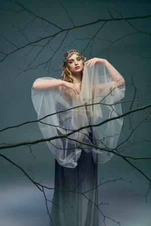 Eine junge Frau in einem weißen Kleid, die eine Fee oder Elfe verkörpert, steht königlich neben einem majestätischen Baum in einem Atelier-Ambiente.