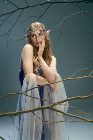 Una joven, parecida a una princesa elfa, posa en un vestido azul en un ambiente mágico de estudio.