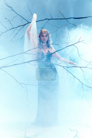 Eine junge Frau in einem blauen Kleid, das einer Elfenprinzessin ähnelt, steht anmutig im mystischen Nebel und verströmt einen ätherischen Charme.