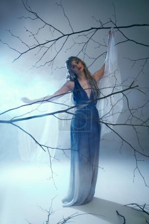 A young woman, resembling an elf princess, stands elegantly in a blue dress in front of a majestic tree.