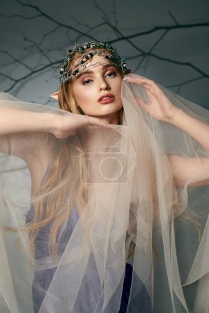 Foto de Una joven, vestida como una princesa elfa de cuento de hadas, está de pie con un velo elegantemente cubierto sobre su cabeza. - Imagen libre de derechos
