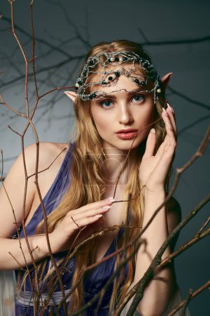 A young woman in a blue dress, resembling an elf princess, wears a chain around her head in a fairy and fantasy-inspired studio setting.