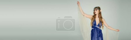 Photo for A young woman, resembling an elf princess, stands wearing a blue dress with a flowing veil on her head in a studio setting. - Royalty Free Image