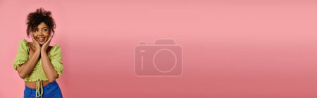 Téléchargez les photos : Femme afro-américaine élégante pose sur fond rose vibrant. - en image libre de droit