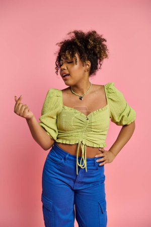 Stylish African American woman poses in vibrant yellow top and blue pants.