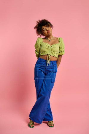 Photo for Stylish African American woman in yellow top and blue pants posing against a vibrant backdrop. - Royalty Free Image