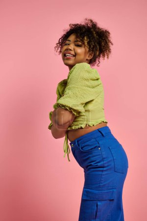 Téléchargez les photos : Femme afro-américaine élégante pose en haut jaune vif et pantalon bleu. - en image libre de droit