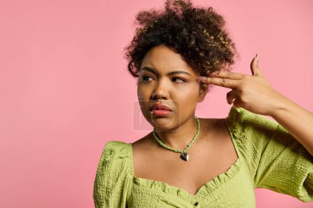 Foto de Una mujer afroamericana con estilo en un top amarillo escucha atentamente poniendo su mano en su oreja. - Imagen libre de derechos