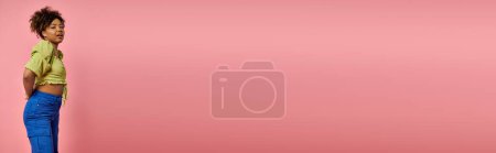 Téléchargez les photos : Femme afro-américaine élégante frappant une pose devant un mur rose vibrant. - en image libre de droit