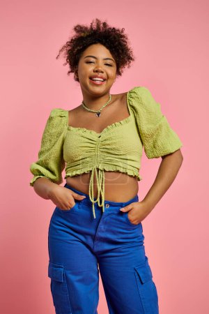 Stylish African American woman posing in yellow top and blue pants on a vibrant backdrop.