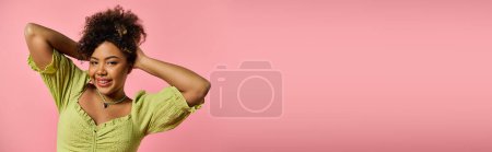 Téléchargez les photos : Femme afro-américaine élégante dans une chemise jaune tient ses cheveux gracieusement. - en image libre de droit