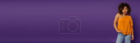 Photo for A young girl standing confidently in front of a purple wall. - Royalty Free Image
