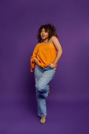 Téléchargez les photos : Femme afro-américaine élégante pose en haut orange vibrant sur fond coloré. - en image libre de droit