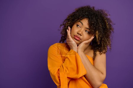 A beautiful African American woman with curly hair poses stylishly against a vibrant backdrop.