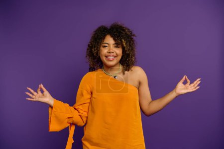 Photo for Stylish African American woman in orange top holds out hands. - Royalty Free Image