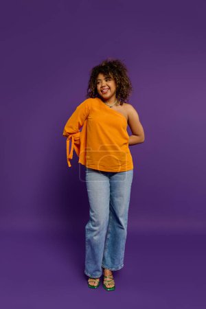 A stylish African American woman poses in front of a vibrant purple background.