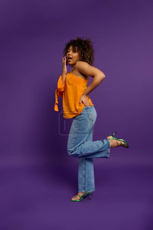 Mujer afroamericana con estilo en top amarillo y jeans azules.