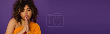 Téléchargez les photos : African American woman in stylish attire pulling a funny face with curly hair on vibrant backdrop. - en image libre de droit