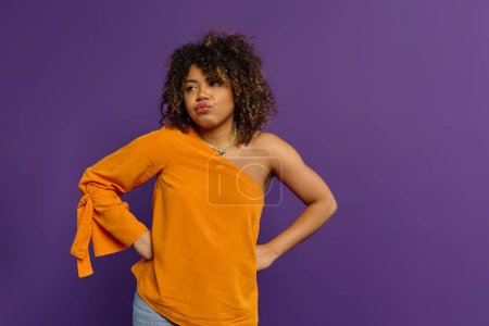 Photo for Stylish African American woman striking pose in front of vibrant purple backdrop. - Royalty Free Image