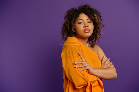 Téléchargez les photos : Femme afro-américaine élégante frappe une pose en haut orange vibrant. - en image libre de droit