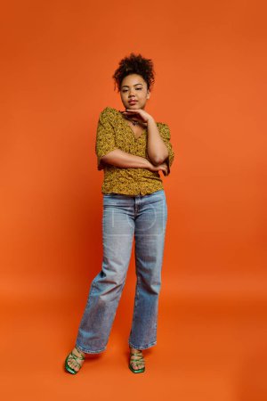 Stylish African American woman posing in front of a vibrant orange backdrop.