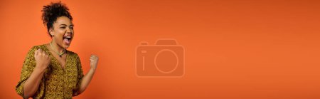 Photo for Stylish African American woman stands with open mouth against orange backdrop. - Royalty Free Image