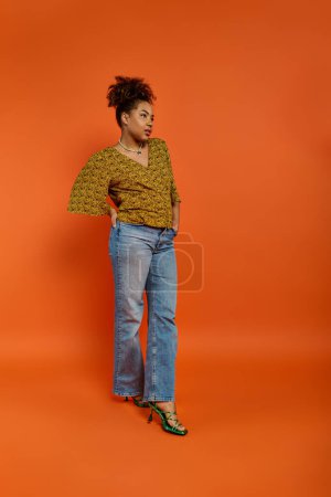Elegante mujer afroamericana posando sobre un vibrante fondo naranja.